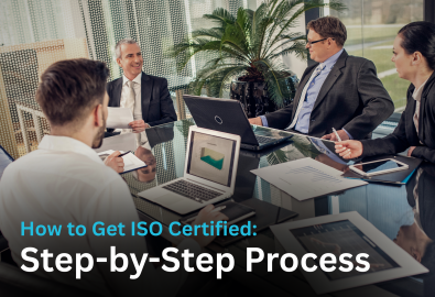 "Business professionals in a meeting discussing ISO certification process with laptops and documents, representing step by step ISO certification guidance"